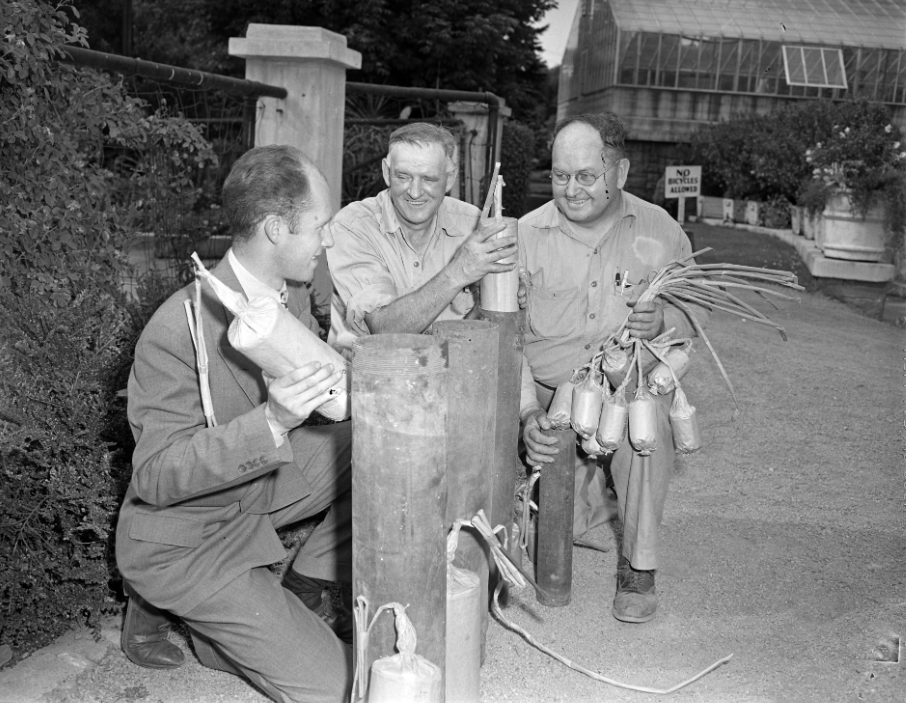 Three men gather and light fireworks.